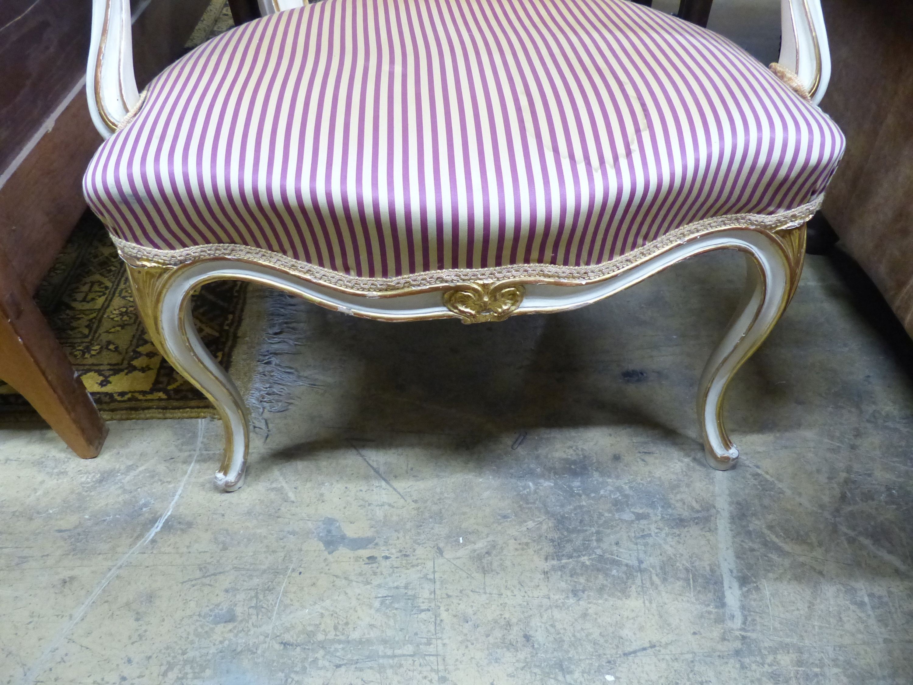 A 19th century French Louis XV style parcel gilt, cream painted fauteuil, with striped upholstery.